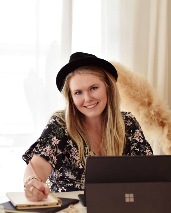 Sarah from Poppins Copy, Freelance Marketing Service Toowoomba, sits at a table writing.